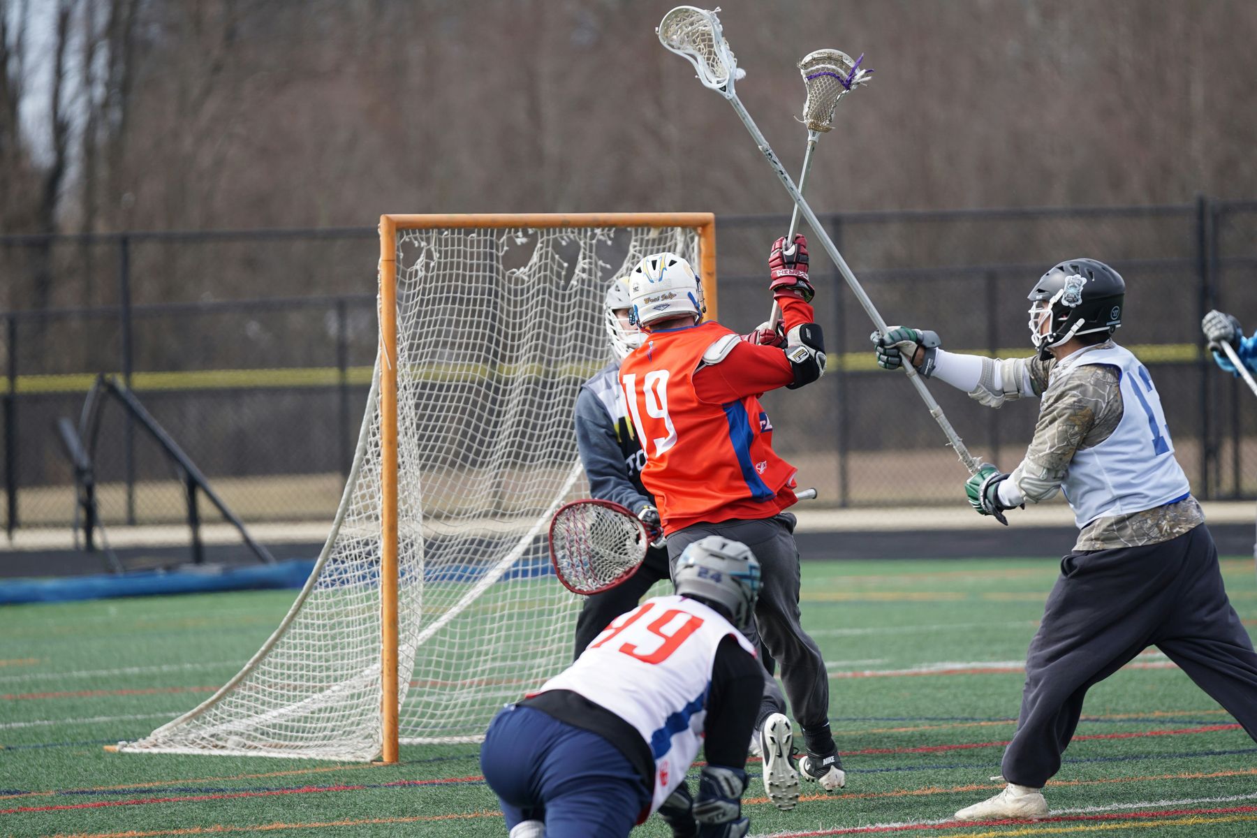Lacrosse players competing in front of the goal during a game