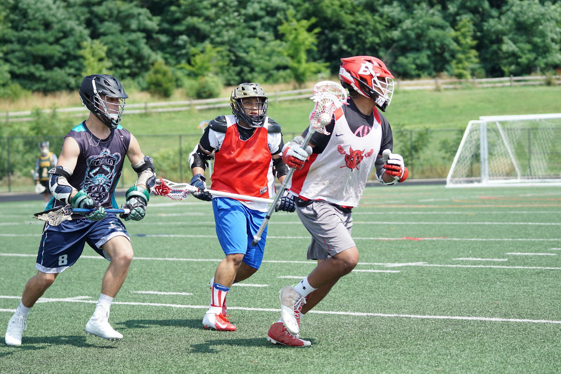 Adult men playing a pickup lacrosse game on a turf field